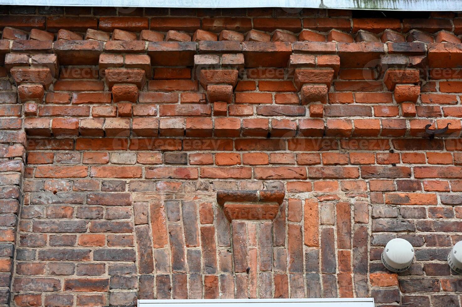 a brick wall with decorative brickwork and a clock photo