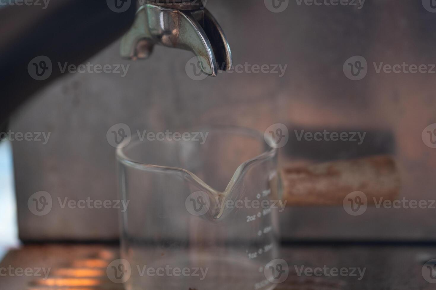 Prepare empty glass shot for espresso poured from coffee machine. photo