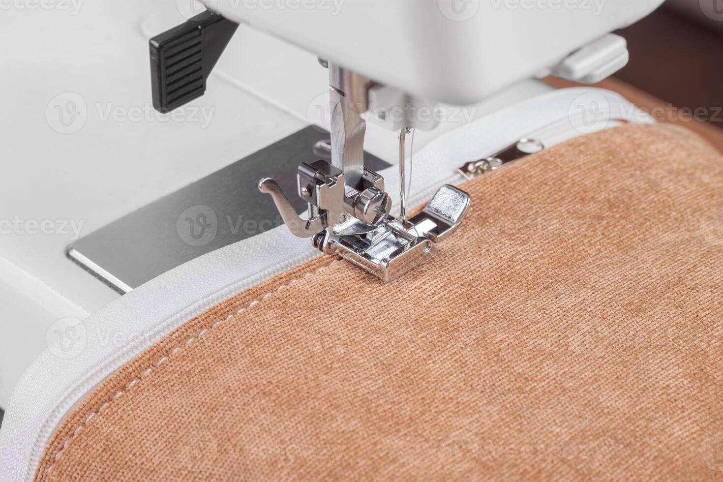 Modern sewing machine special presser foot with beige fabric and zipper, closeup photo