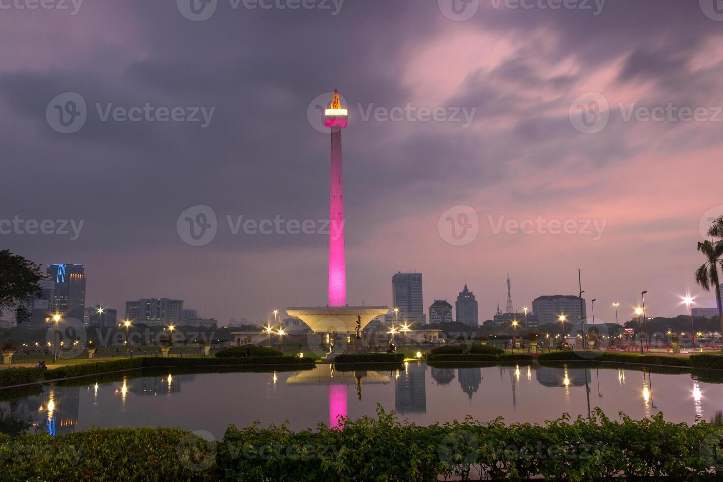 Beautiful landscape of Monas Monument in Medan Merdeka Square, Jakarta and office buildings reflected on water in the dusk, Indonesia photo