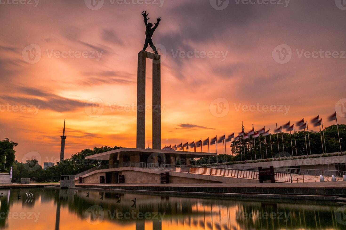 West Irian Liberation Monument in the Lapangan Banteng Bulls Field formerly Waterloo Square in Jakarta. Long exposure photography with beautiful golden sunrise. photo
