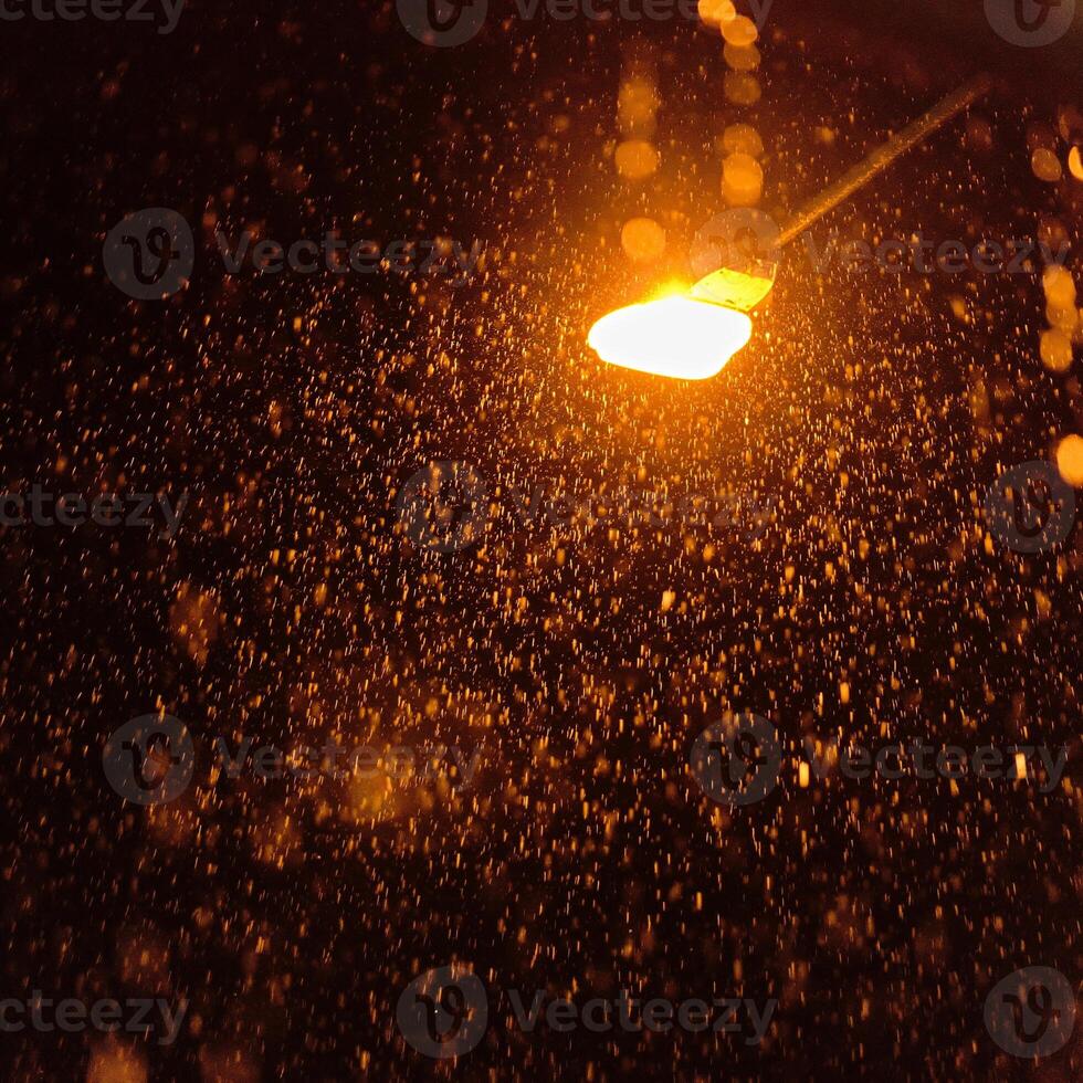 Glowing light bulb is hanging orange. Car parking indicator blinking at night on highway.It is raining heavily. The light of the lantern illuminates the drops of rainwater. photo