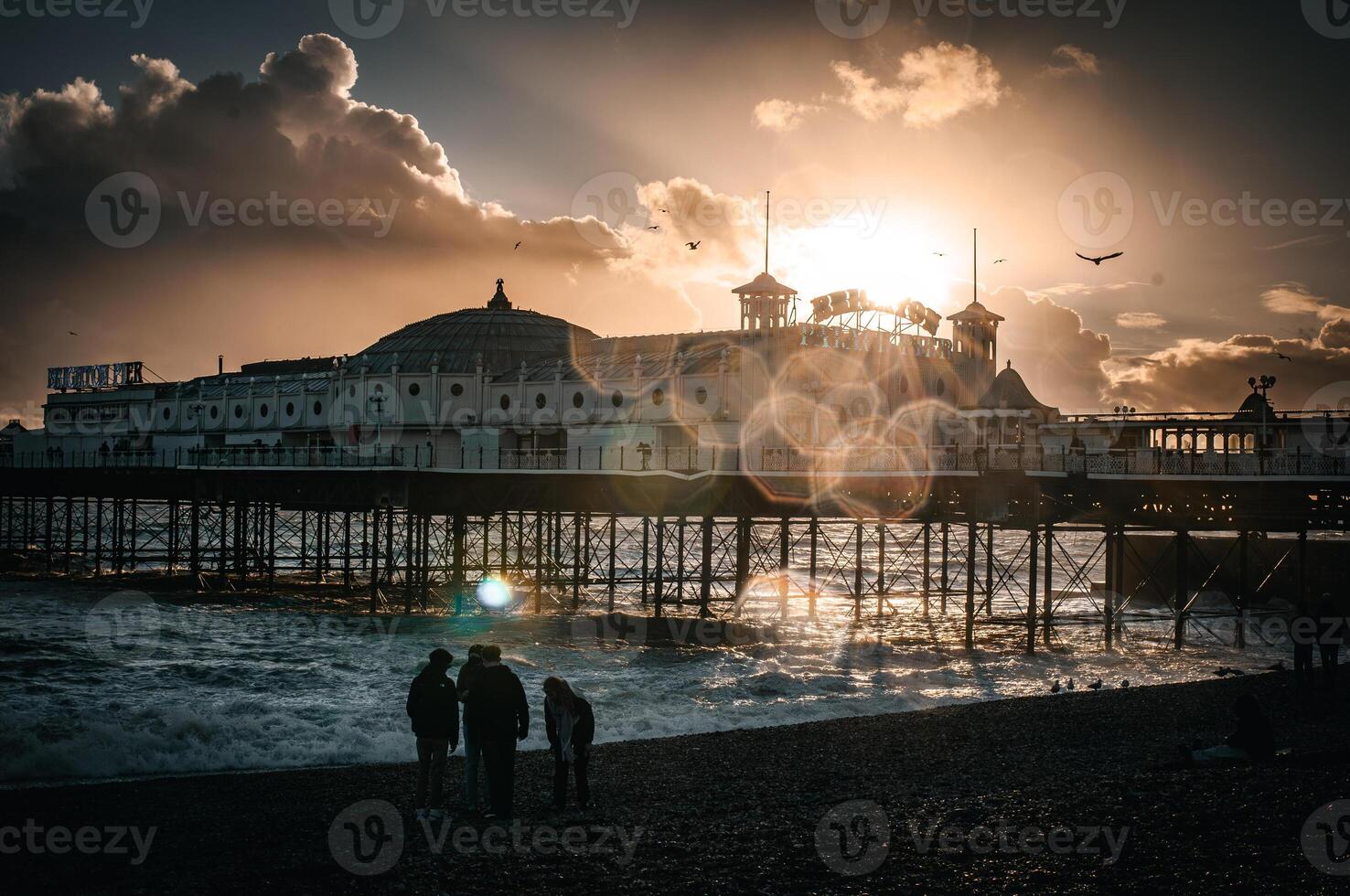 Brighton pier in a spot of sun with people on the beach, East Sussex, UK photo