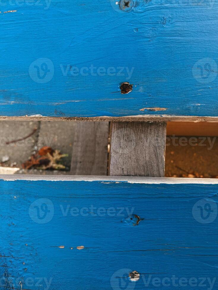Closeup of vibrant blue painted wooden surface with visible screws and small gap revealing darker piece of wood underneath. Texture of wood. Rustic, handcrafted vibes photo