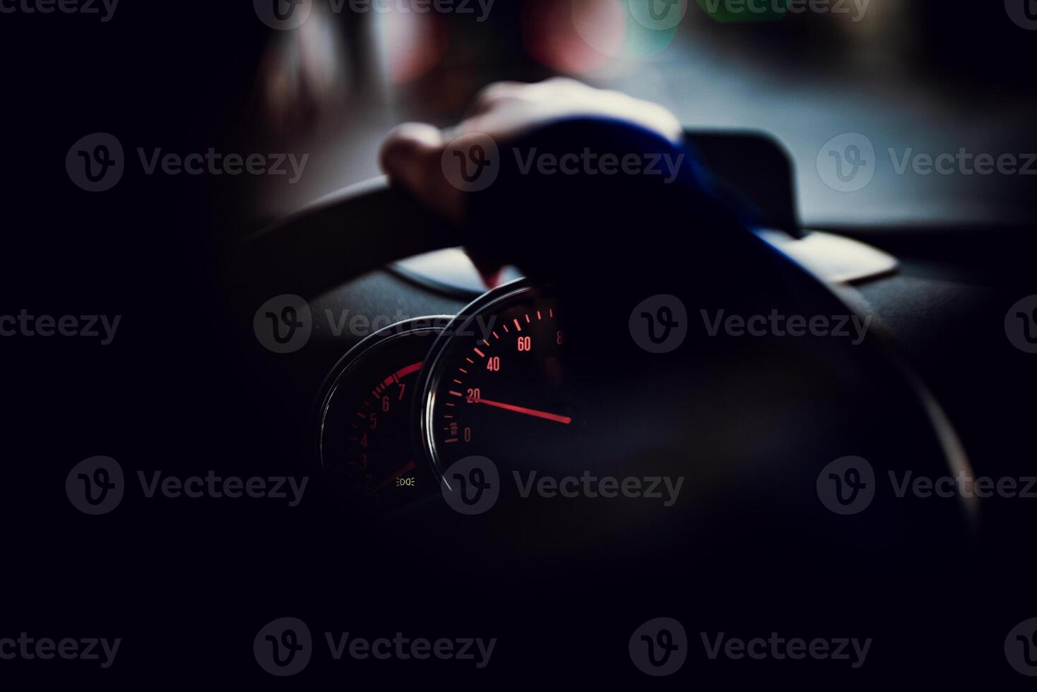 Speedometer instrument cluster visible behind a hand on a steering wheel photo
