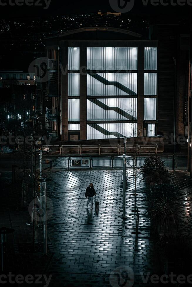 A lady with a suitcase on a wet street after rain at night photo