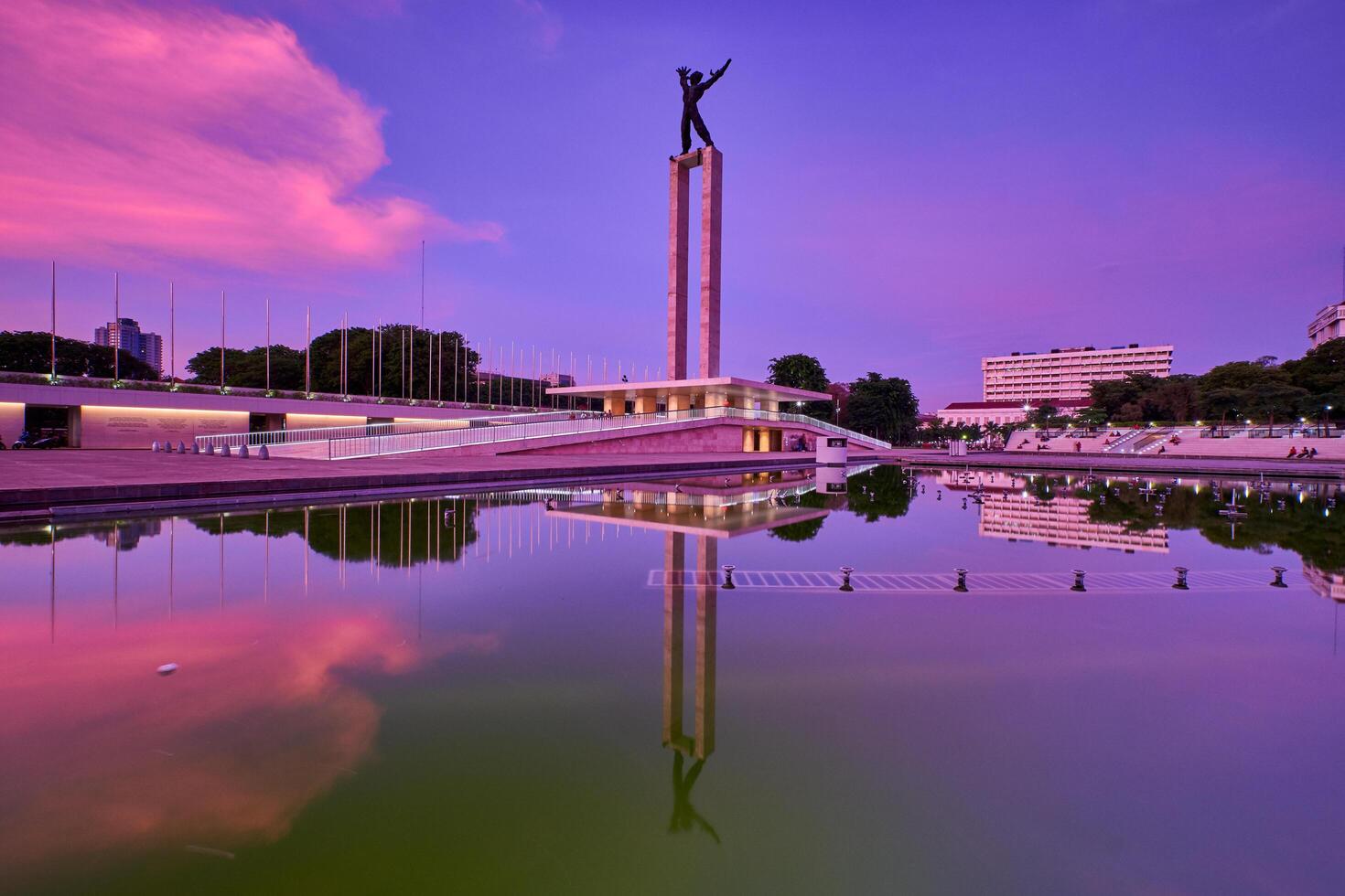 Irian Jaya Liberation Monument, Jakarta in the sunrise with reflection of cloudy sky on water photo