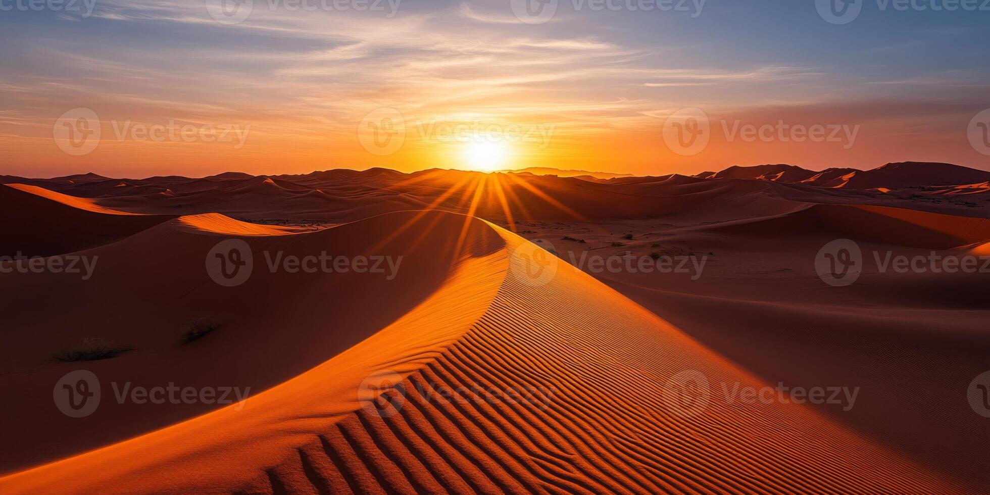 The sun setting behind towering dunes, casting long shadows across the desert photo