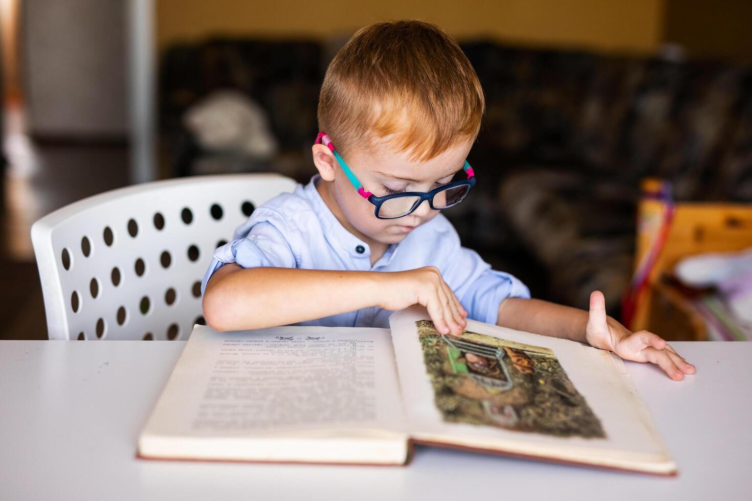 Cute toddler boy with down syndrome with big glasses reading intesting book photo