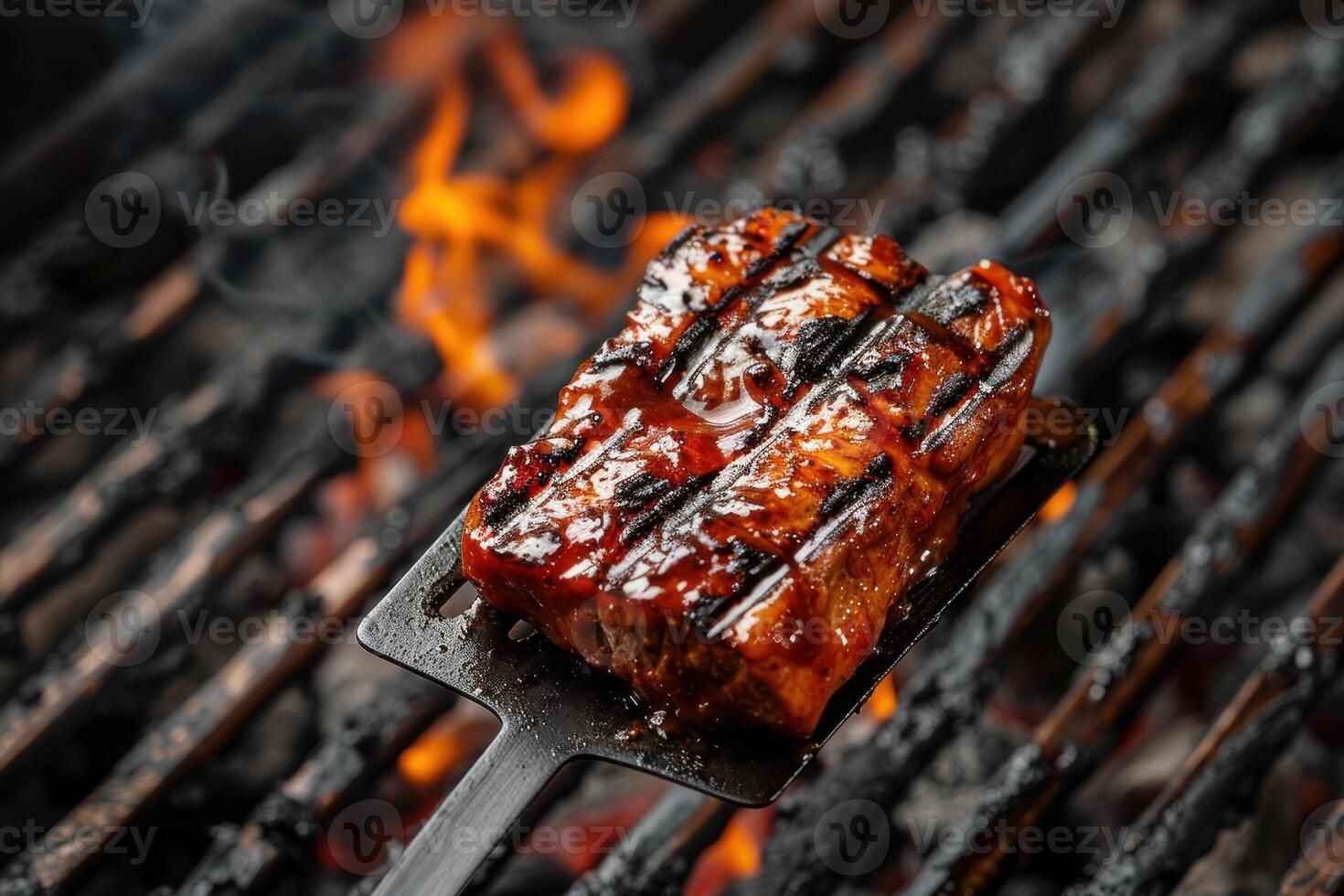 Barbecue spatula holding grilled meat over hot coals photo