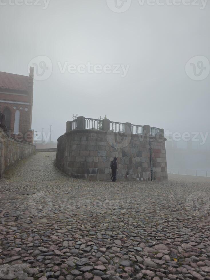 a person standing on a stone path in the fog photo