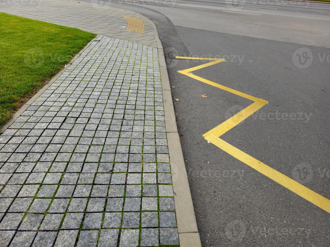a sidewalk with yellow lines and grass on it photo