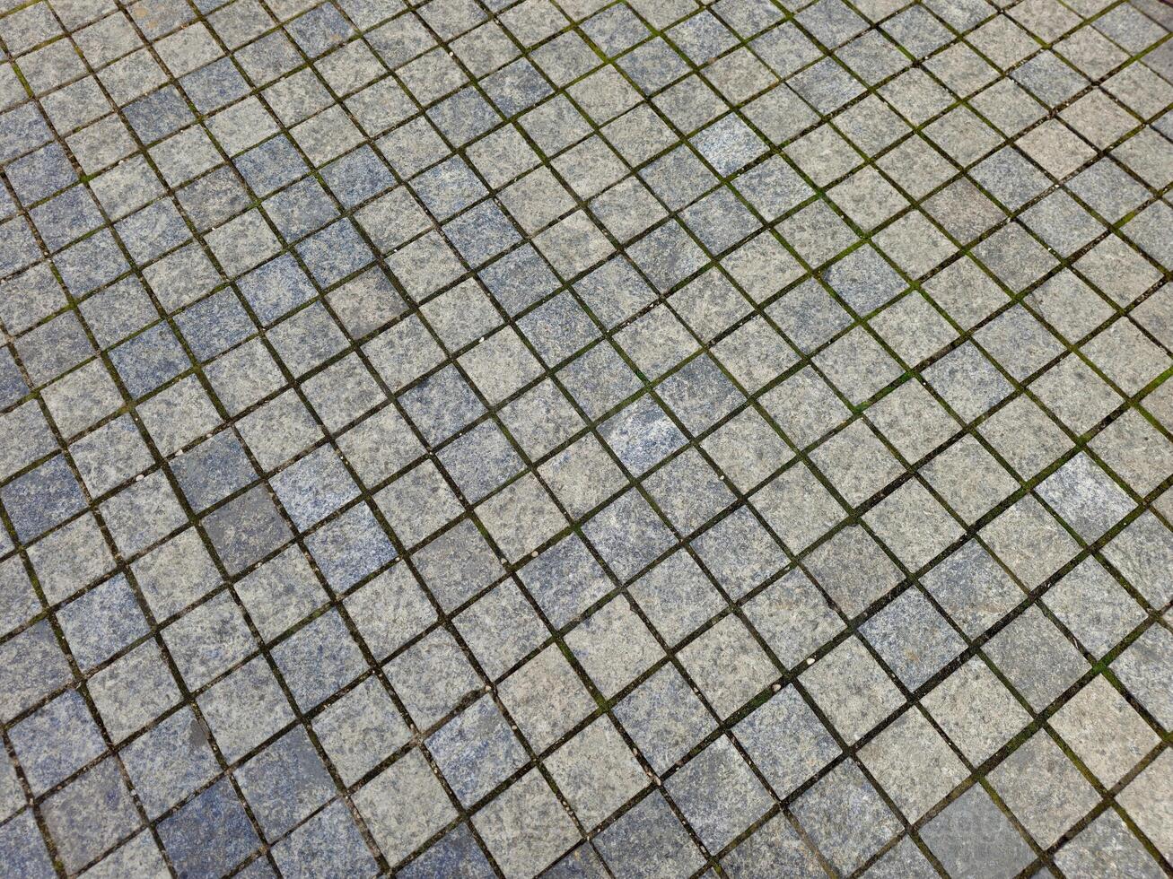 a tiled floor with grass growing on it photo