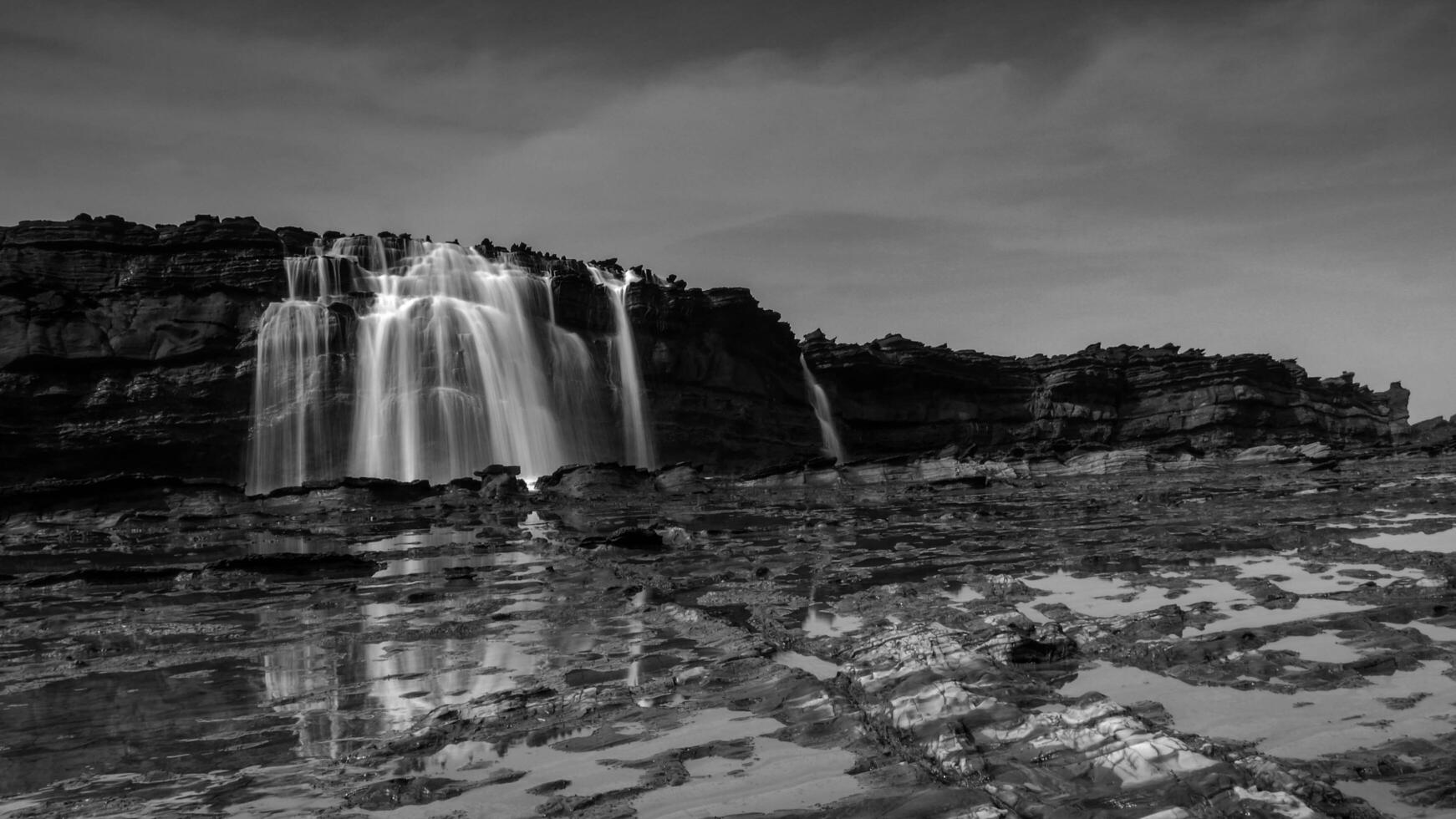 Big waves create beautiful sea views of waterfalls and water flows in Karang Taraje, Sawarna Beach, Indonesia. A favorite location for domestic and foreign photographers to hunt for photos and videos.