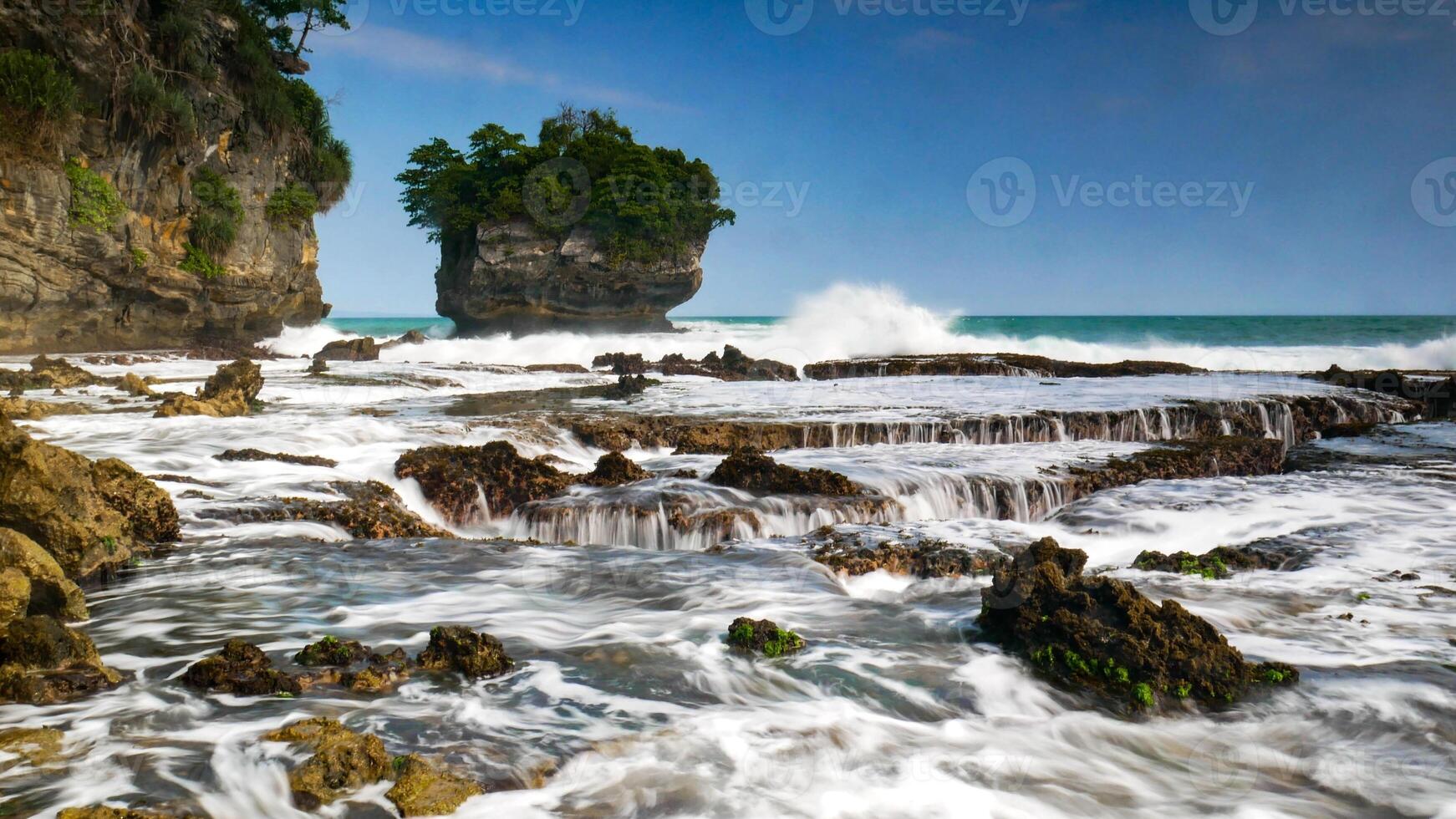 The beauty of Karang Bokor Beach, Sawarna, Banten. Large rock decorated with trees in the middle of the sea are the main attraction of this view with the crashing waves add to the dynamic impression. photo