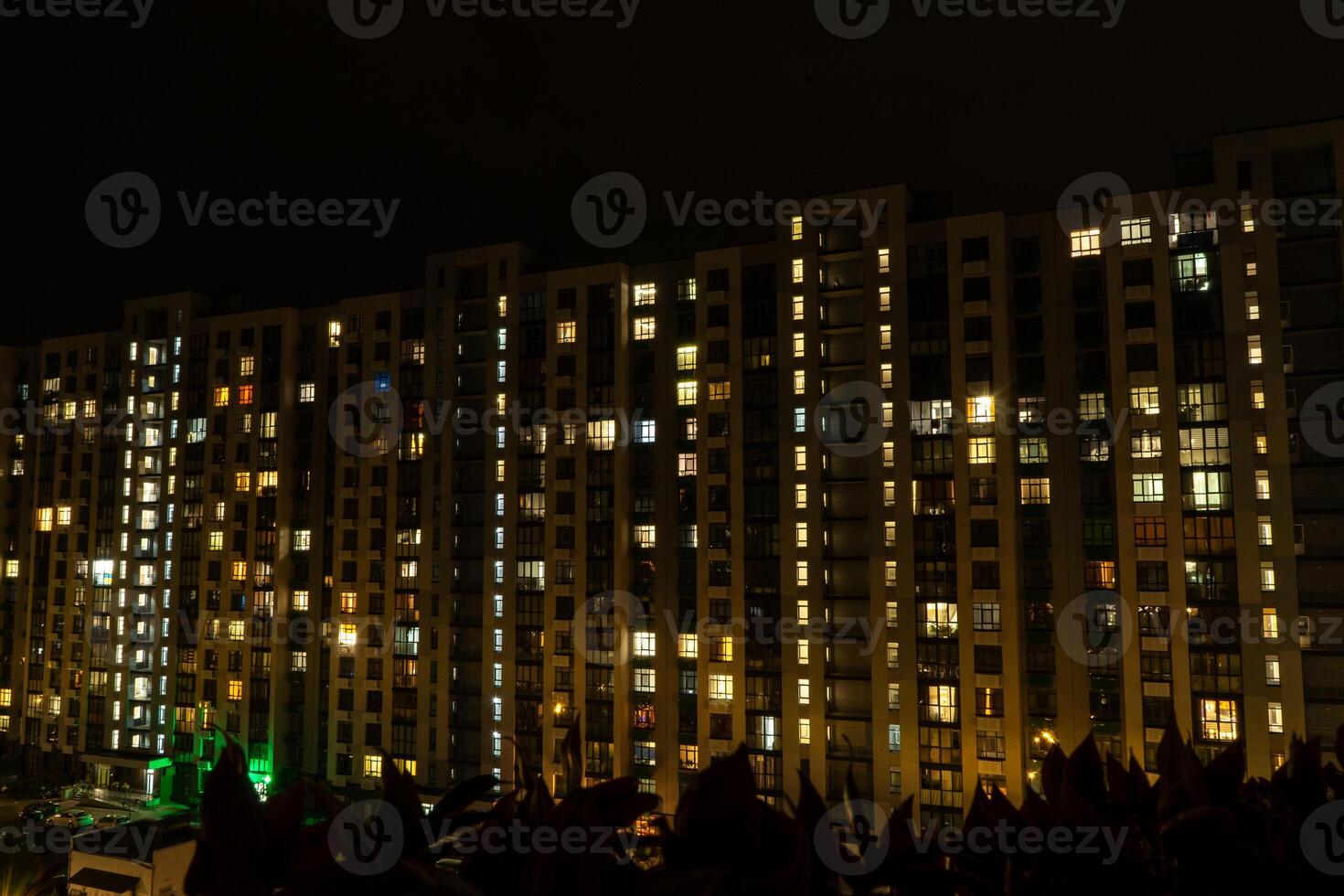 Night city. Multistorey residential building. The windows of the house glow in the dark. photo
