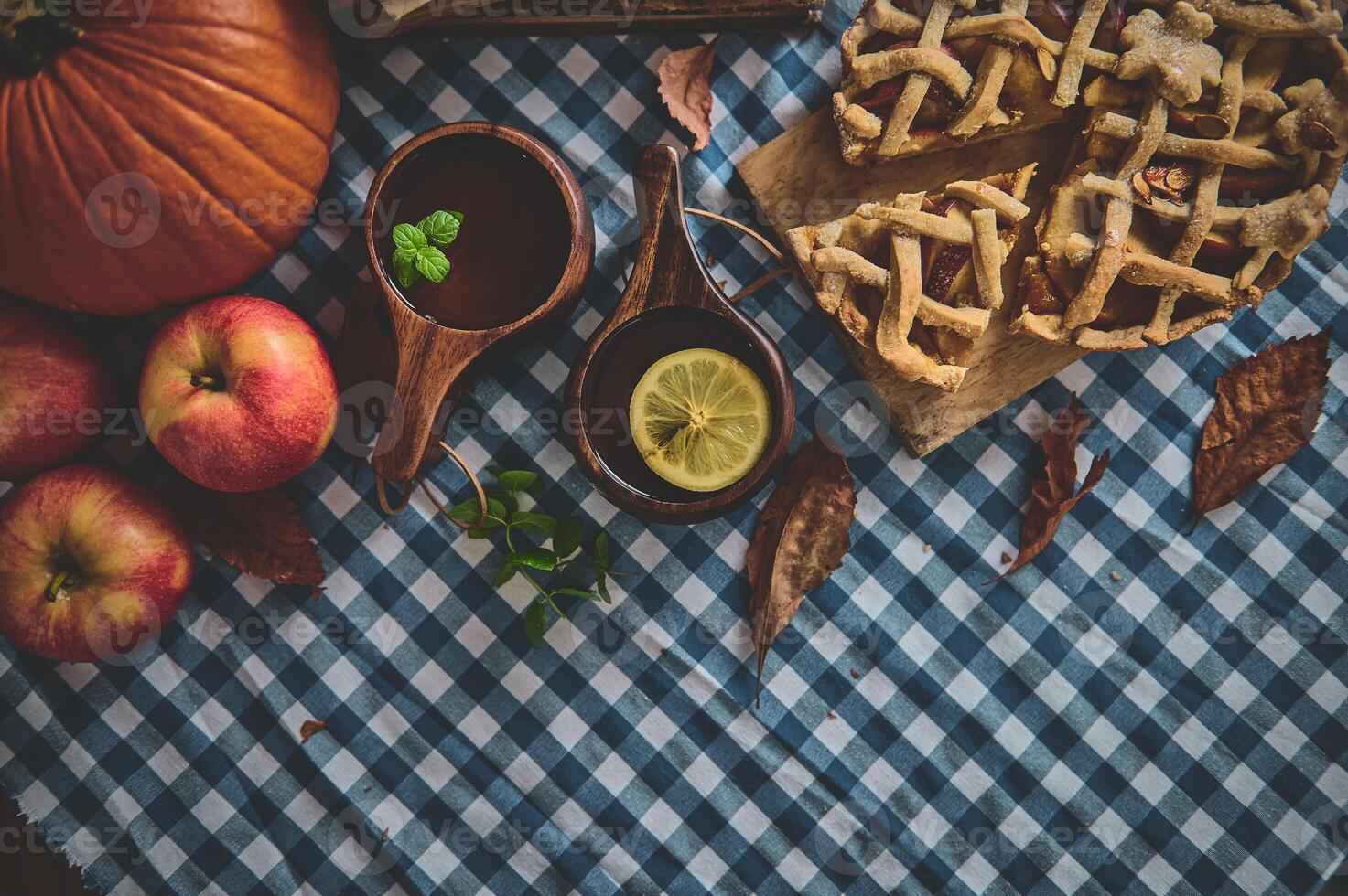Autumn harvest table with freshly baked apple pie and warm beverages on a cozy gingham tablecloth photo