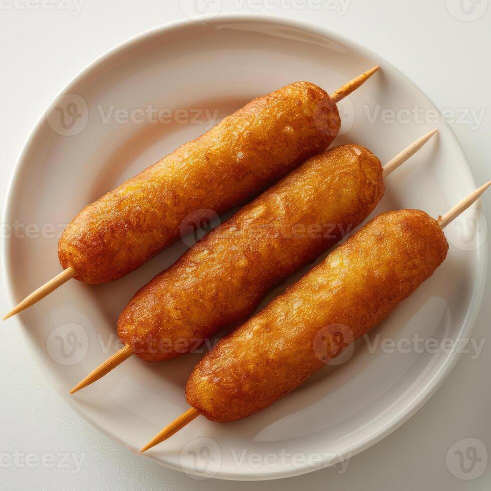 three hot dogs on a white plate with toothpicks on them photo