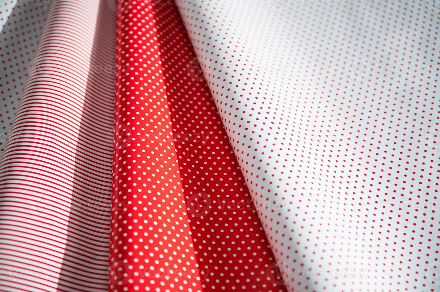 Colorful red and white polka dot and striped pattern paper with light and shadows creating a cheerful and festive atmosphere. photo