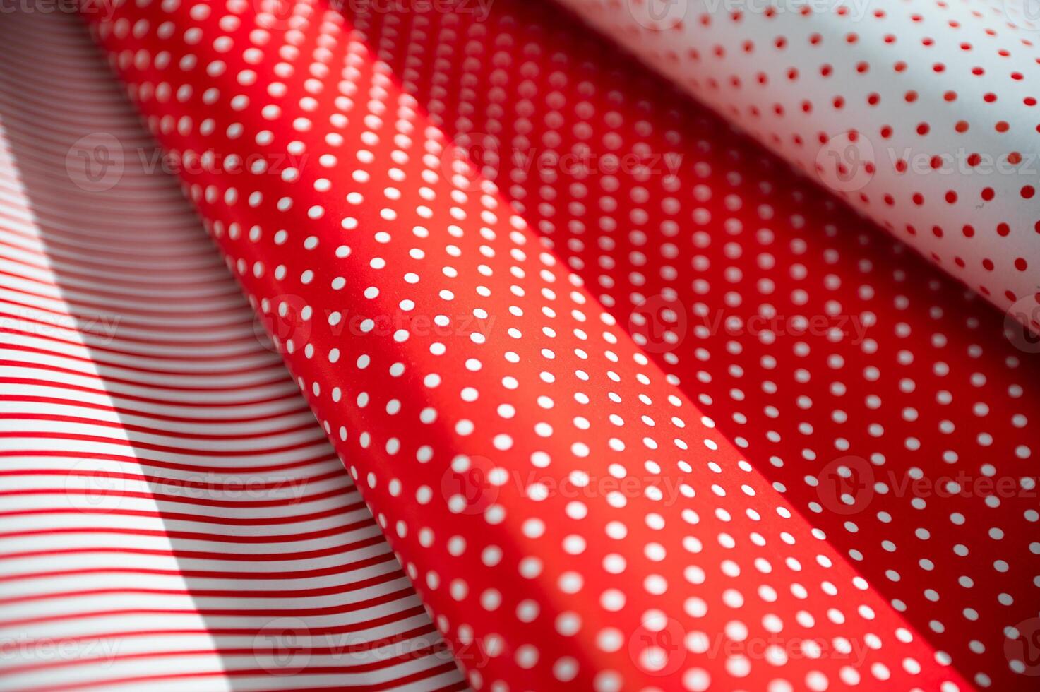 Close-up of vibrant red and white polka dot and striped wrapping paper rolls creating a festive and cheerful design perfect for birthdays, holidays, or special gift occasions. photo