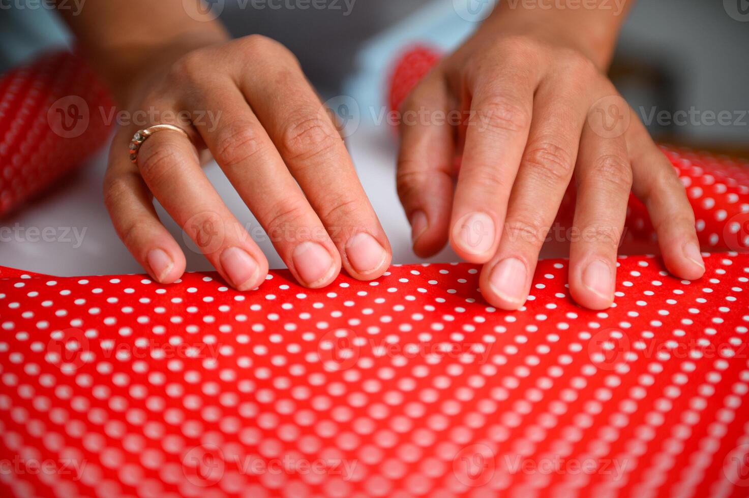 Close-up of hands wrapping a gift in red polka dot paper, highlighting the art of gift preparation photo