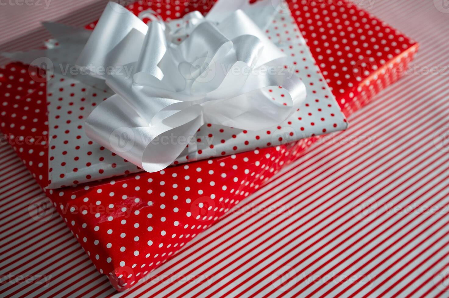 Festive gift boxes wrapped in red and white polka dot paper with a large white ribbon bow, perfect for holiday celebrations, birthdays, or special occasions. Elegant and eye-catching presentation. photo