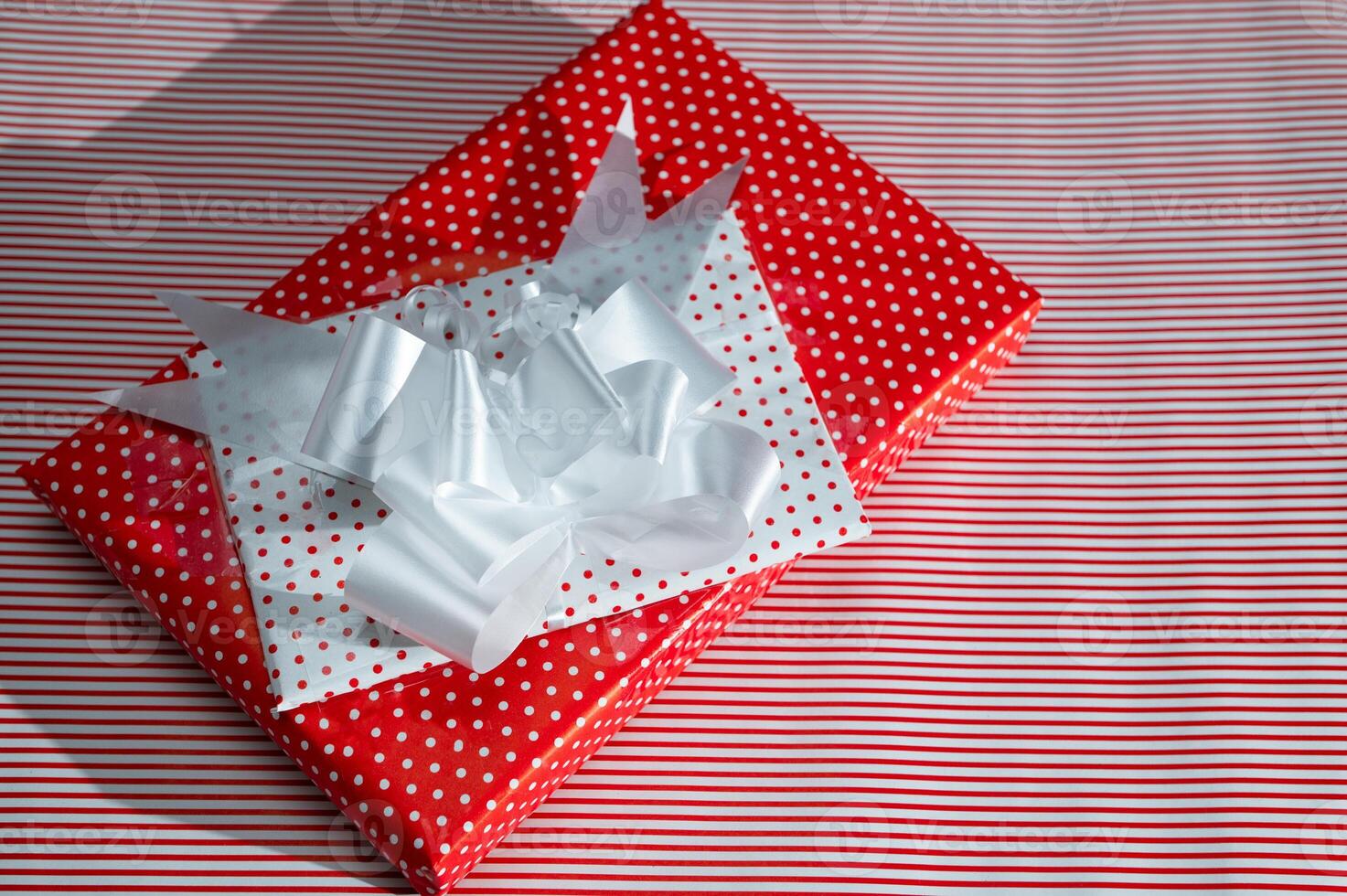 Beautifully wrapped red and white polka dot gift box with decorative white ribbon, perfect for Christmas or festive celebrations photo
