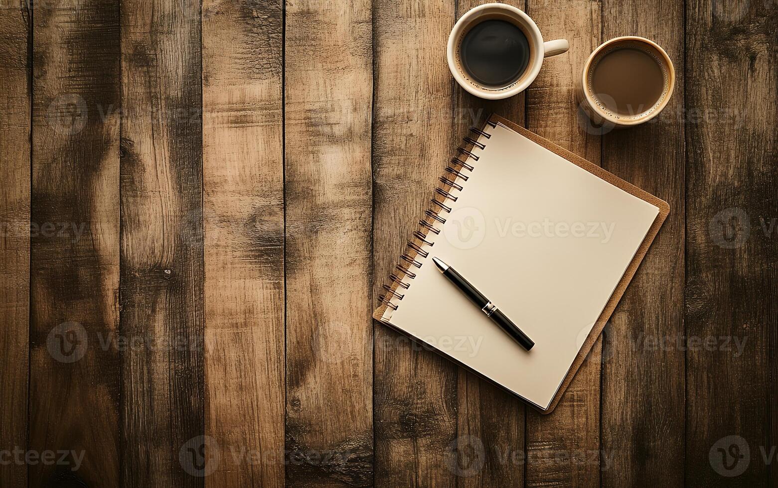 Cozy workspace setup on wooden table with coffee cups, blank notebook, and pen, perfect for brainstorming or creative writing photo