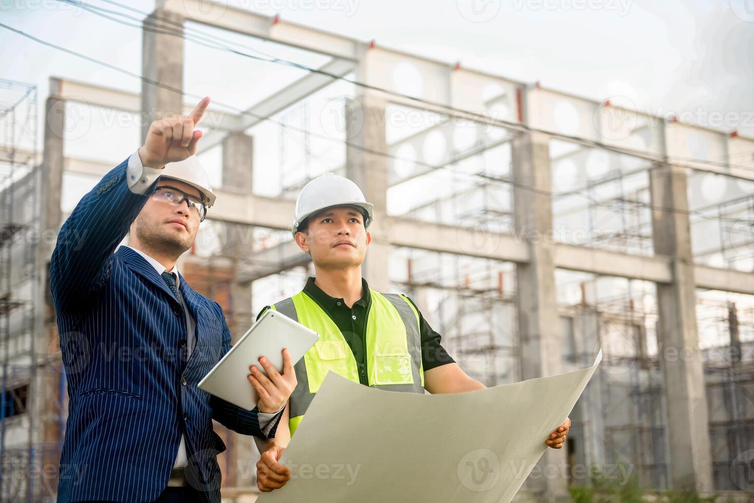 Engineer and architect monitor the progress of building construction plan and verify their accuracy. photo