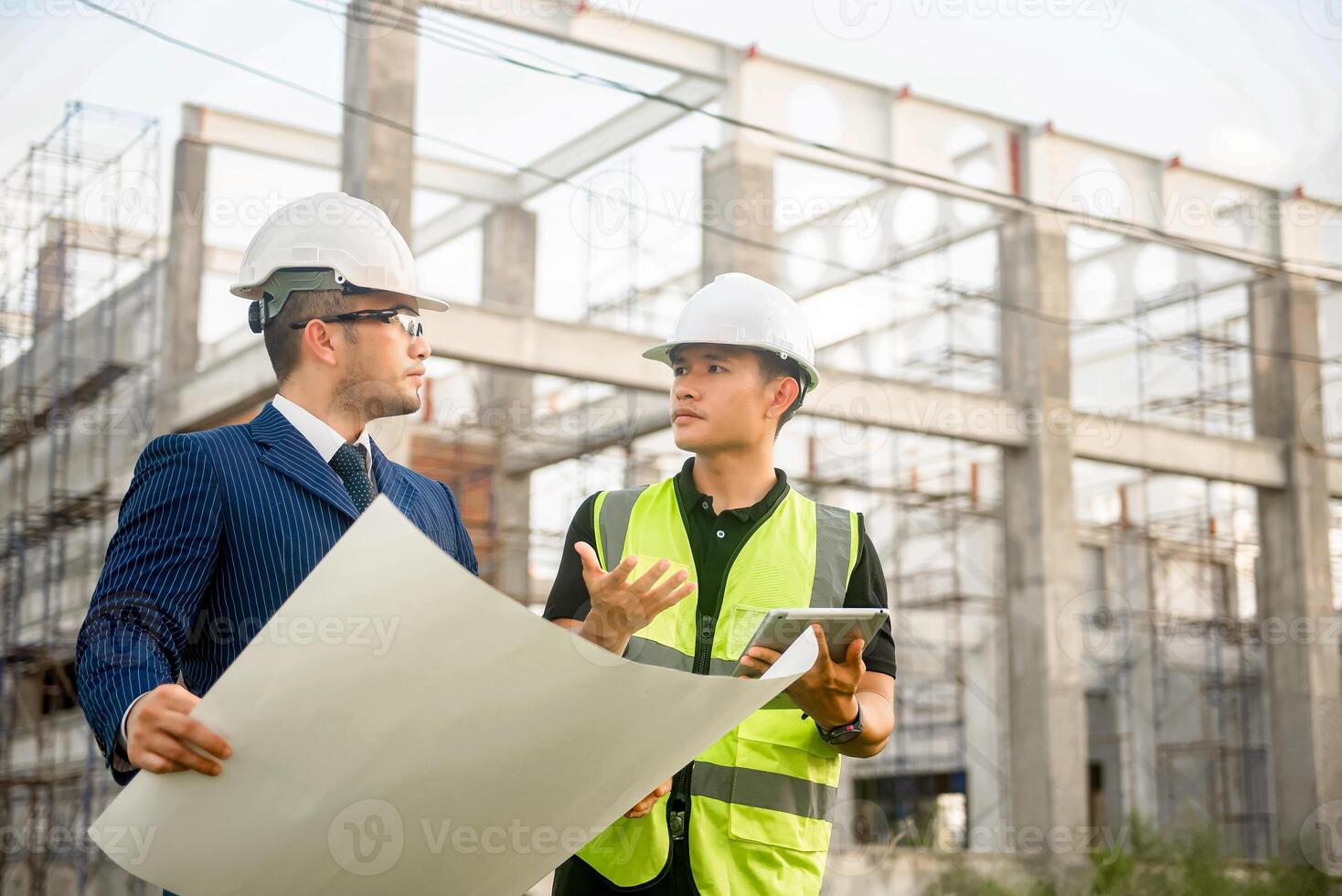 Engineer and architect monitor the progress of building construction plan and verify their accuracy. photo