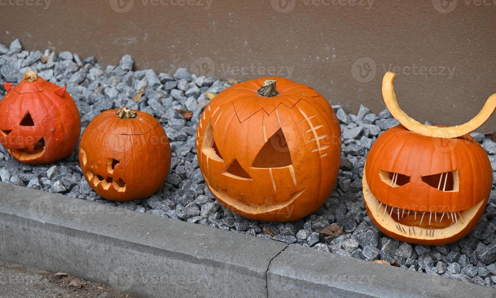 a group of carved pumpkins lined up on a stone wall photo