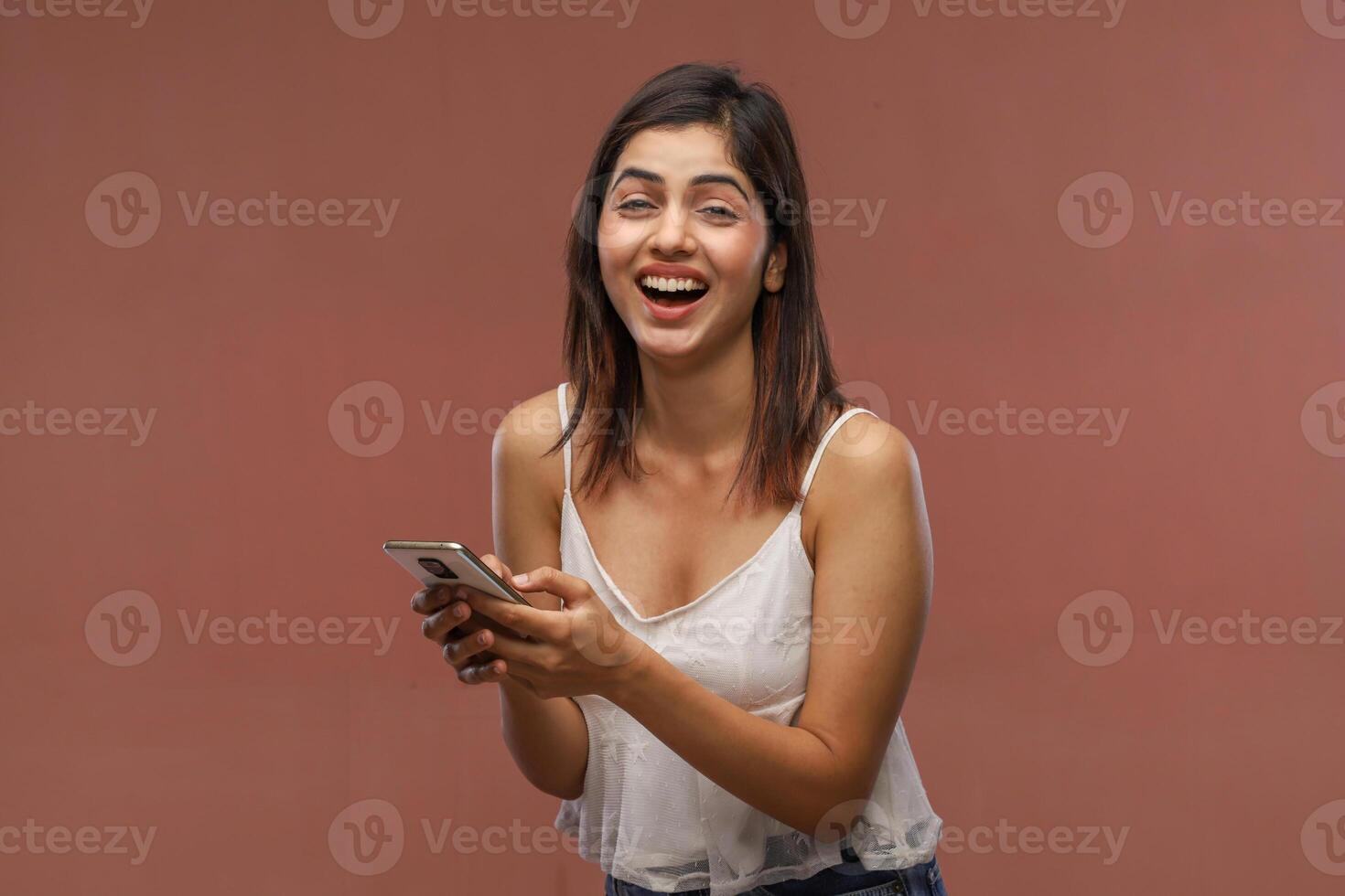 A Stunning Girl Is Laughing While Holding Her Phone photo