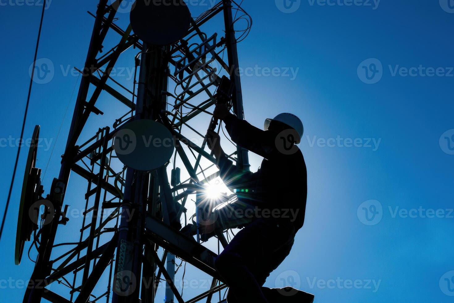 Silhouette of a telecommunication engineer working on a cell tower photo