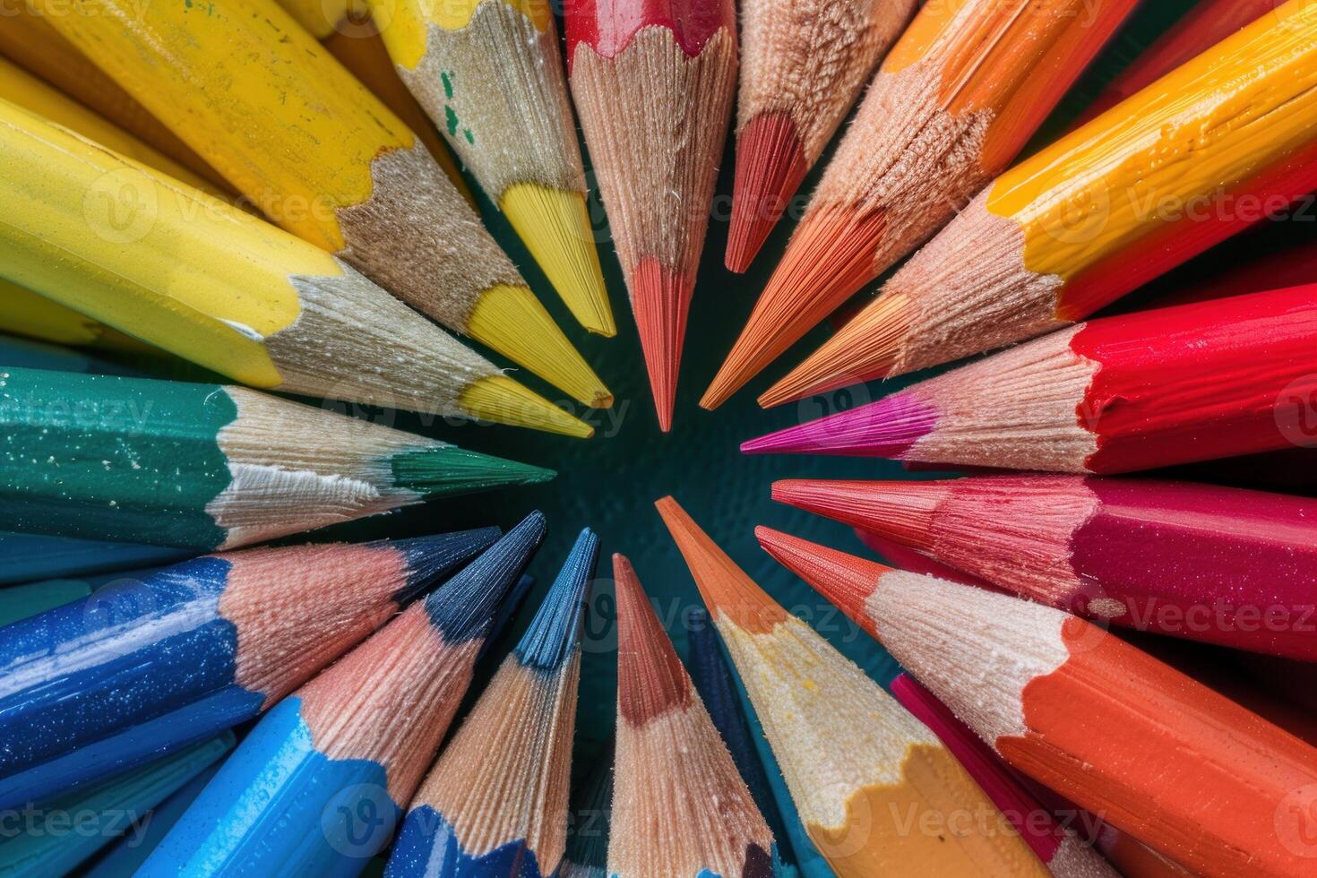 Colorful sharpened pencils forming circle on dark background photo