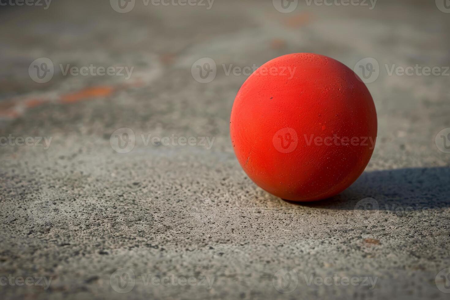 Red rubber ball resting on pavement photo