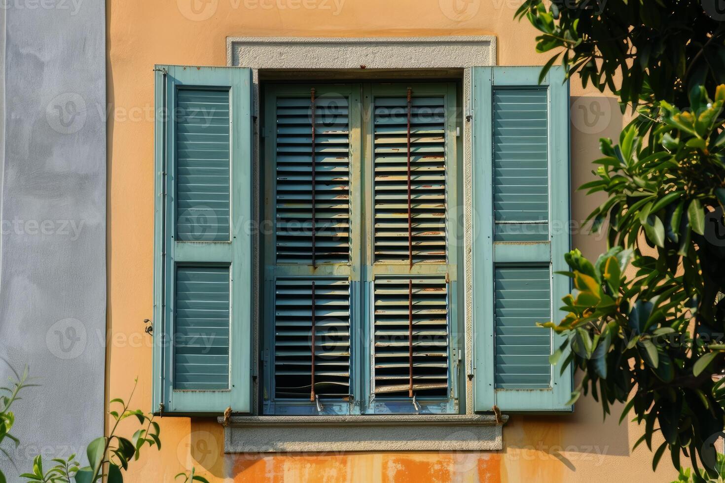Old turquoise window with shutters is half open on a yellow wall photo