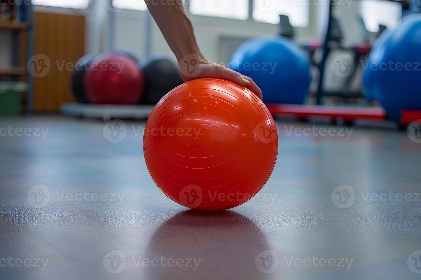 Physiotherapist picking up red exercise ball in rehabilitation center photo