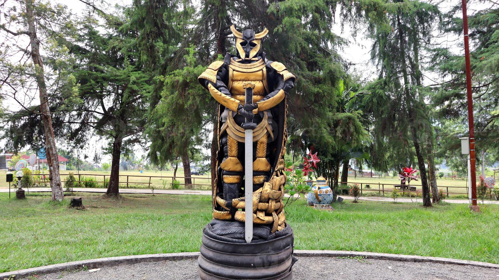 Statues of ancient warlords with swords made from used tires are painted in golden yellow and black photo