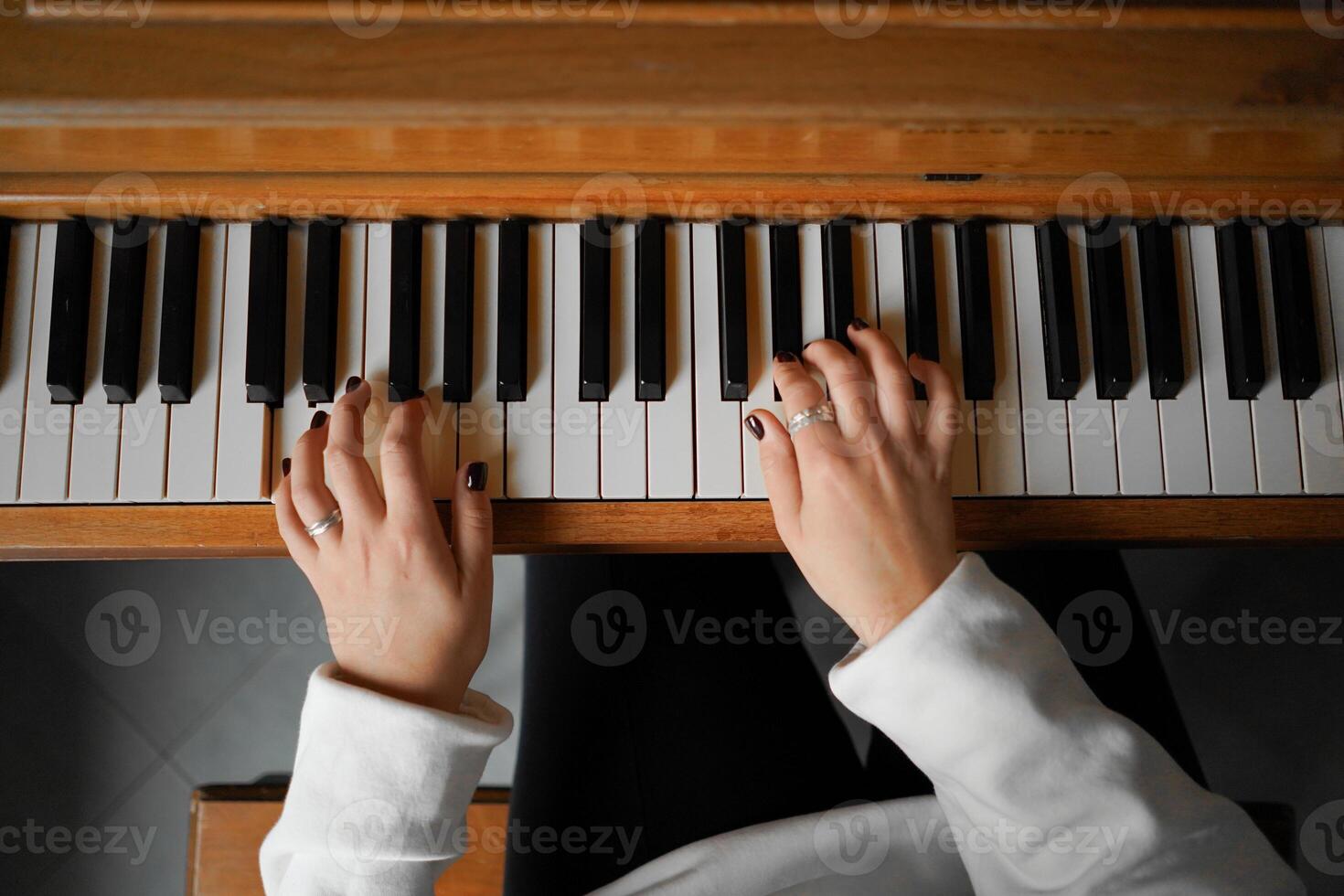 A woman with curly hair sits at a piano, enjoying the music she creates photo