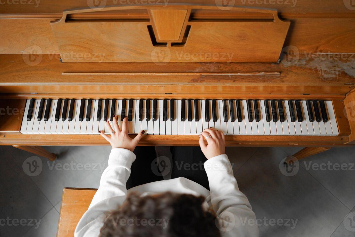 A woman with curly hair sits at a piano, enjoying the music she creates photo