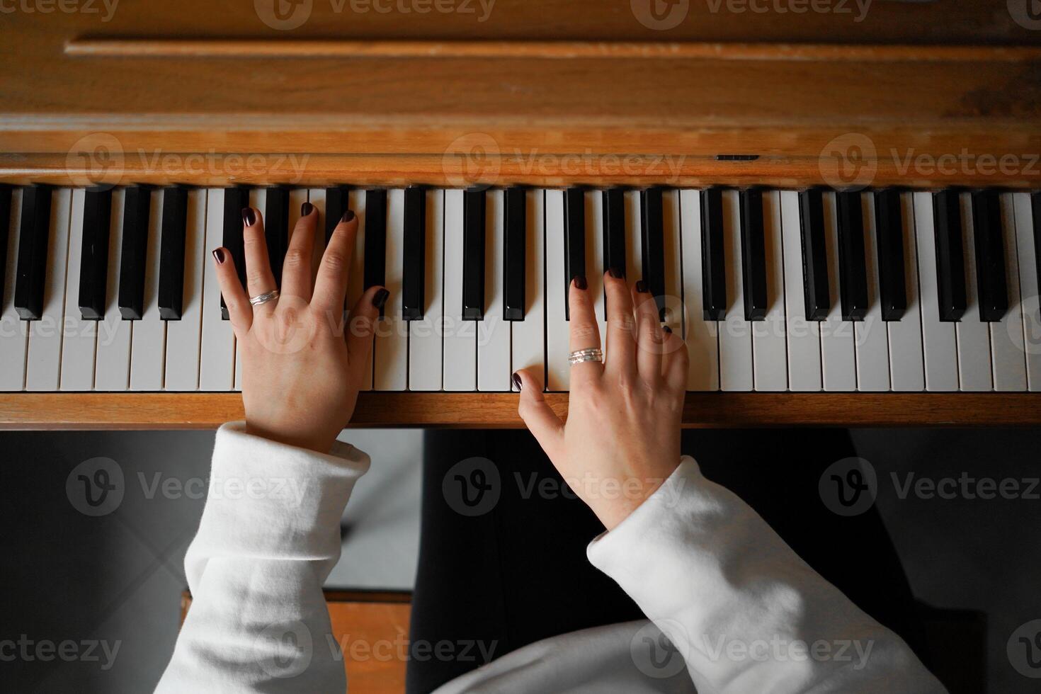 A woman with curly hair sits at a piano, enjoying the music she creates photo