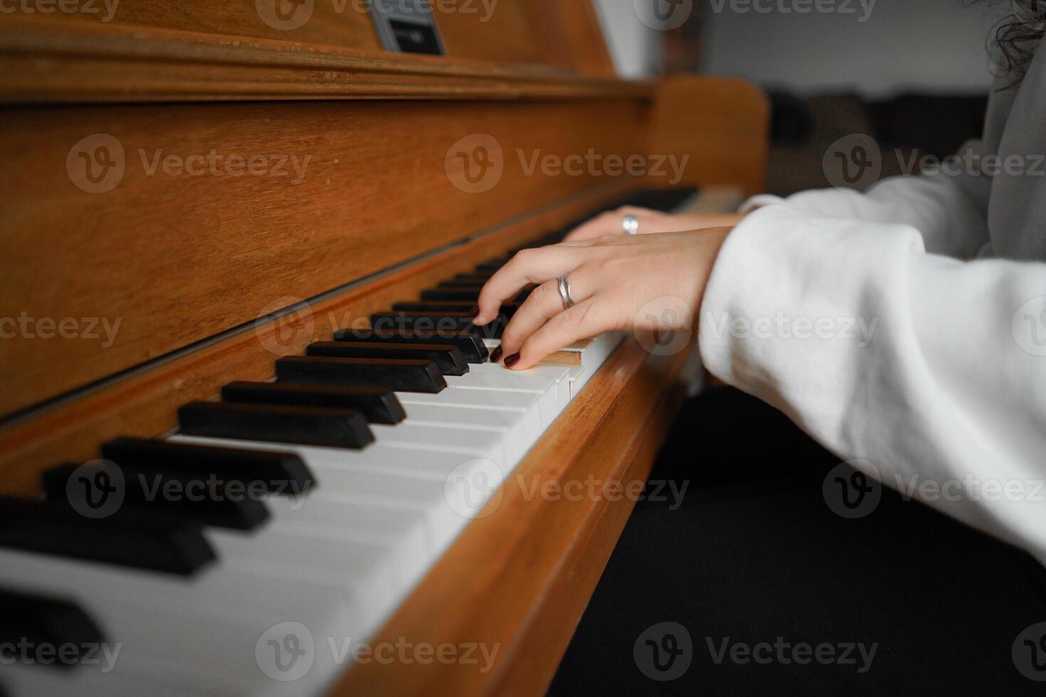 A woman with curly hair sits at a piano, enjoying the music she creates photo