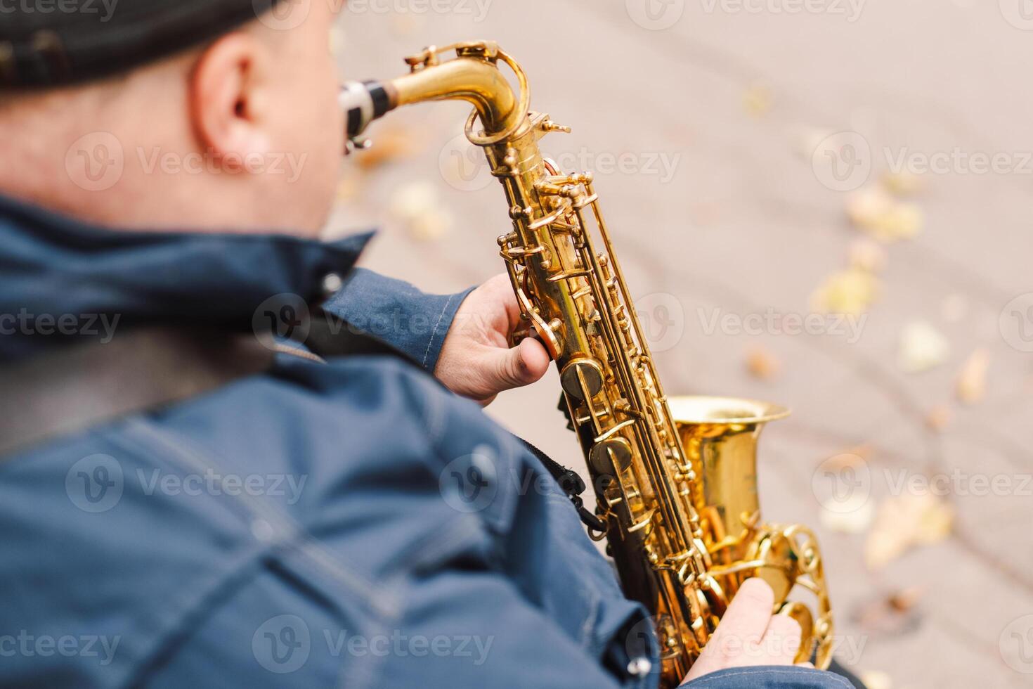 A saxophonist performs in a serene park during autumn while seated on a bench photo