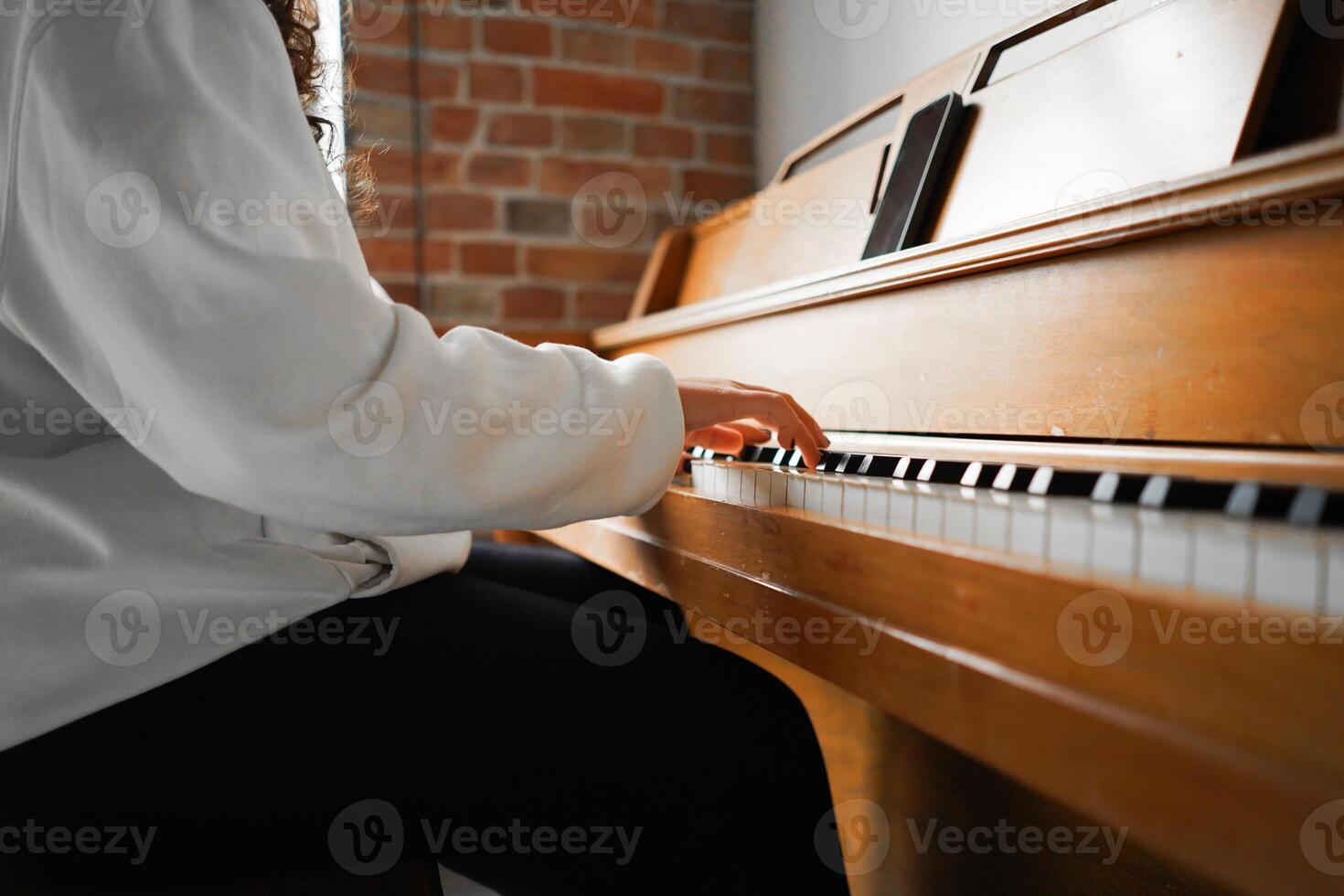 A woman with curly hair sits at a piano, enjoying the music she creates photo