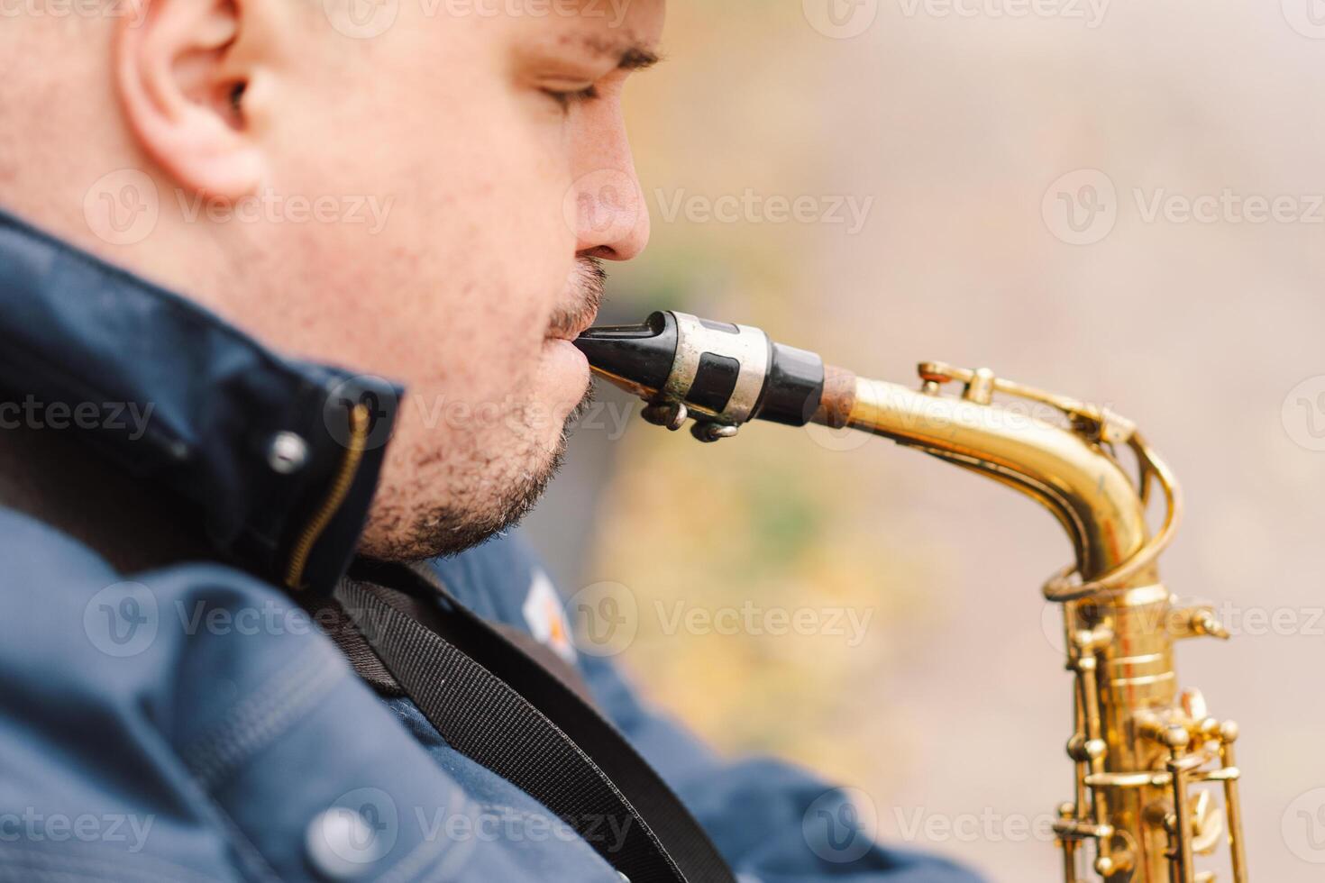 A saxophonist performs in a serene park during autumn while seated on a bench photo