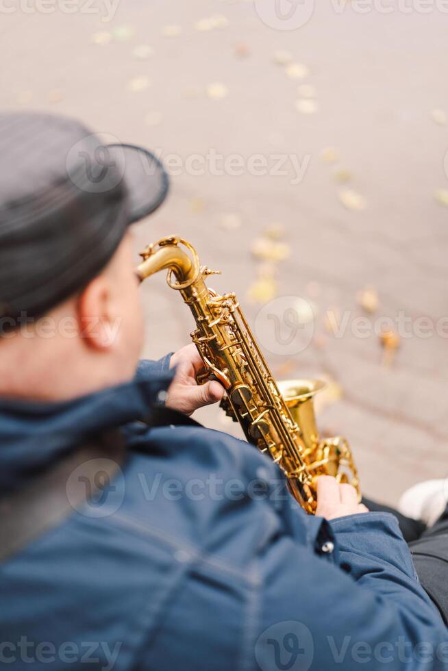 A saxophonist performs in a serene park during autumn while seated on a bench photo