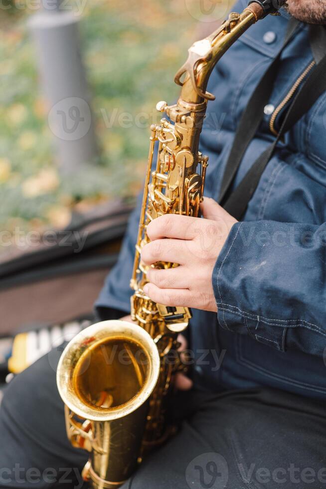 A saxophonist performs in a serene park during autumn while seated on a bench photo