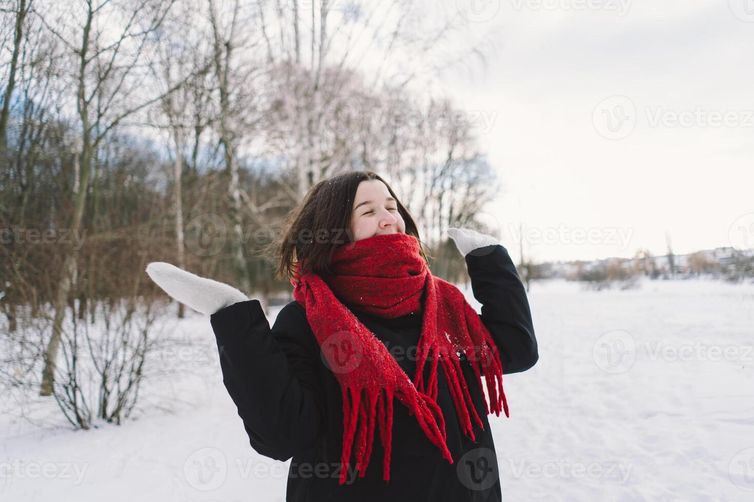 A woman with a red scarf enjoys a snowy winter day in a forest setting beneath a bright blue sky photo