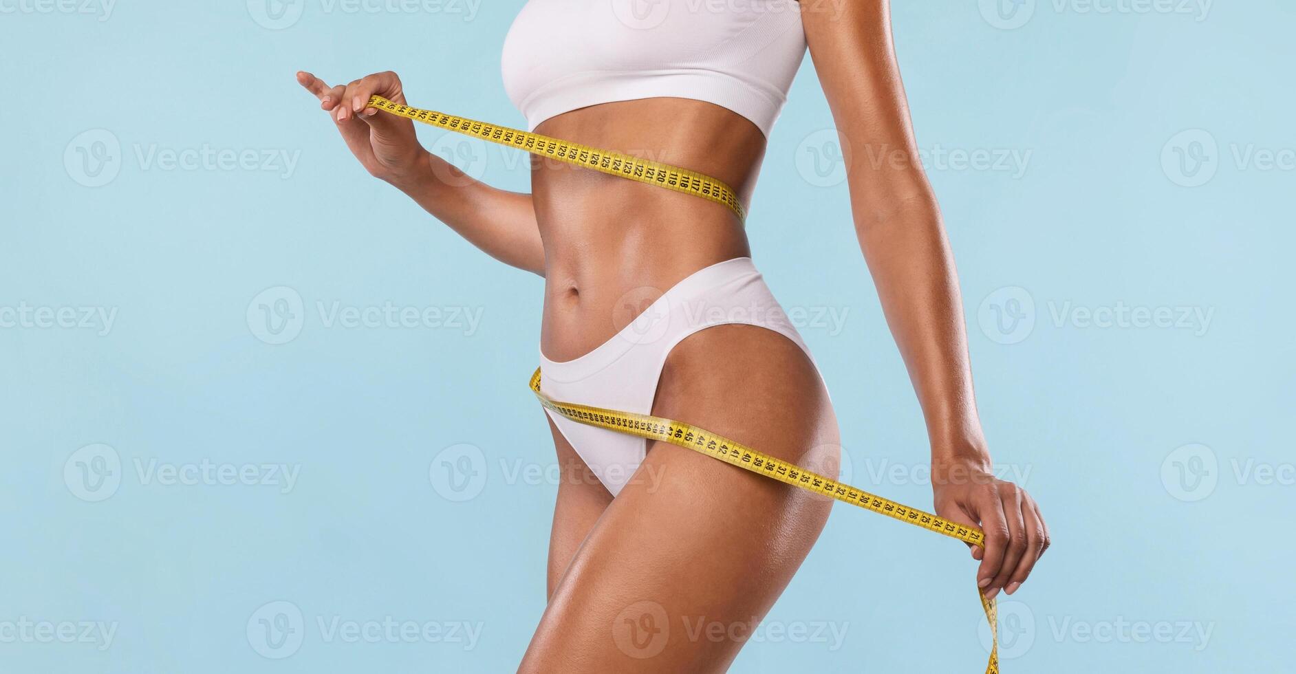 Successful Weightloss And Dieting. Closeup Of Slim Lady Measuring Waist With Tape, Happy About Her Body Parameters, Standing Isolated Over Blue Studio Background. Slimming Concept. Banner photo