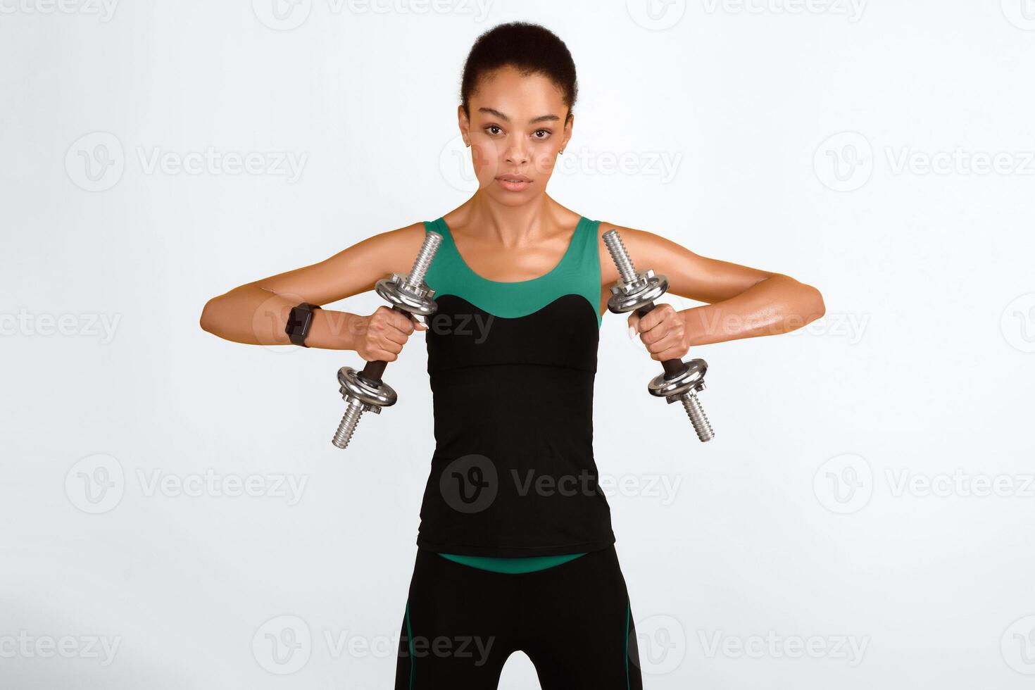 Dumbbell Workout. Determined African American Woman Exercising Looking At Camera Standing On Yellow Studio Background photo